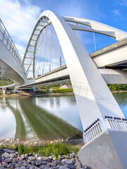 Edmonton arch bridge over river with rocky shore and reflections