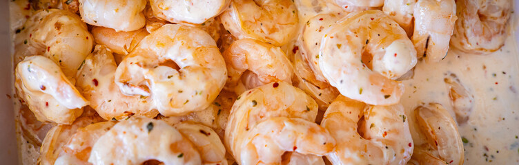Shrimps background texture in white creamy sauce. A lot of shrimps horizontal banner background. Cooked shrimps.