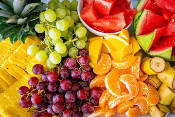 Tropical fruit charcuterie board fruits background, tray plate, light white floral background. Vegan food concept.