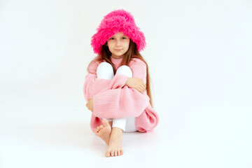 Excited girl model in pink hat posing in studio. Clothes, children's fashion concept. Positive child dancing in studio