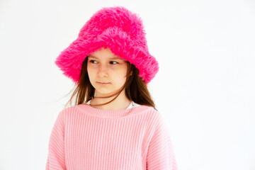 Excited girl model in pink hat posing in studio. Clothes, children's fashion concept. Positive child dancing in studio