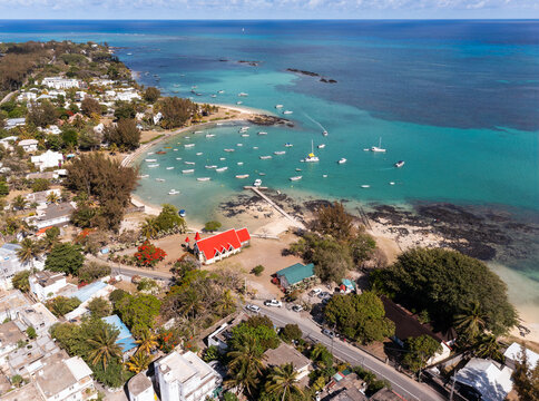 Aerial view of the vibrant red roof of Notre Dame Auxiliatrice church contrasting against the turquoise waters dotted with boats, Cap Malheureux, Riviere du Rempart District, Mauritius.