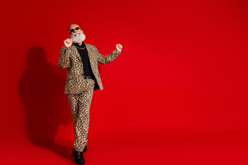 Elderly gentleman in a leopard print suit dancing confidently against a vibrant red background