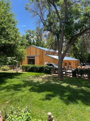 Rustic Yellow Barn Surrounded by Lush Greenery and Trees on a Sunny Day