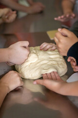 Children knead raw dough at a master class on making buns.
Children's hands touch raw dough