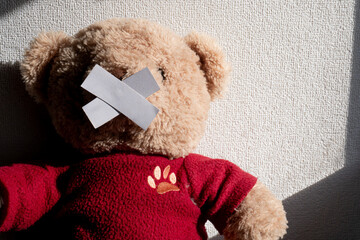 Silenced Bear Toy with Crossed Tape over Mouth Against White Wall.