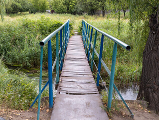 Metal bridge over a small stream into a grassy zone