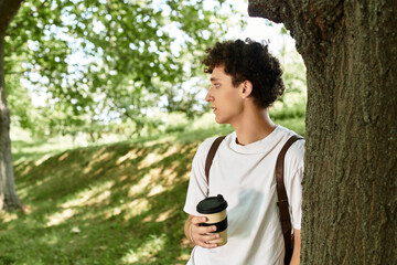 Curly haired young man enjoys a serene moment in a vibrant summer park
