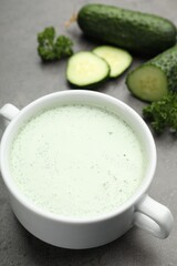 Tasty cucumber soup and fresh vegetables on grey table, closeup