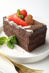 Piece of delicious chocolate cake with strawberry, almonds and mint on table, closeup