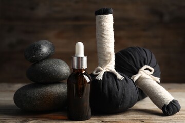 Composition with cosmetic product, spa stones and herbal bags on wooden table, closeup