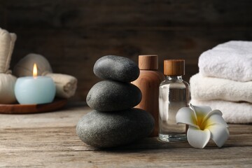 Composition with cosmetic products and spa stones on wooden table, closeup