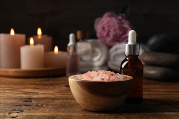 Spa composition with cosmetic products on wooden table against black background, closeup