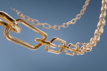 Fototapeta premium Elegant Gold Chains Displayed Against a Soft Blue Background