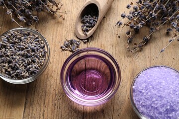 Natural essential oil, sea salt and lavender flowers on wooden background, flat lay