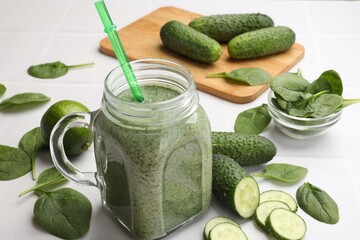 Tasty smoothie in mason jar, spinach leaves and cucumber on white table, closeup