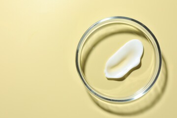 Cosmetic product in Petri dish on pale yellow background, top view. Space for text
