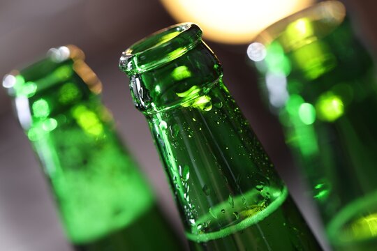 Bottle of tasty beer on blurred grey background, macro view