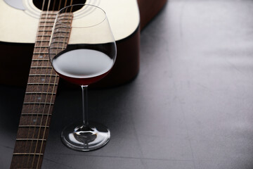 Acoustic guitar and red wine on grey table, closeup. Space for text