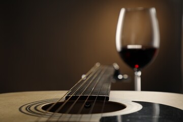Acoustic guitar and glass of red wine on black background, closeup. Space for text