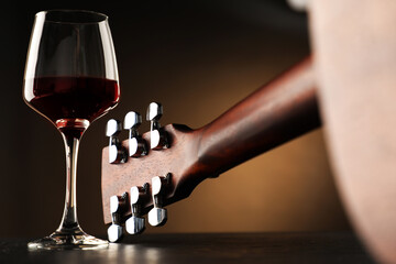 Acoustic guitar and glass of red wine on black table, closeup