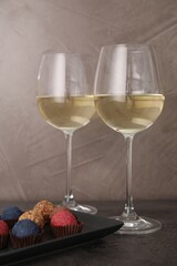 Tasty wine in glasses and truffle bonbons on grey table, closeup