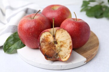 Spoiled apple and good ones on white table, closeup