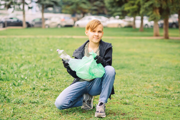 Teenager kid boy picking up trash plastic bottles in the park. Volunteer concept. Ecology,...