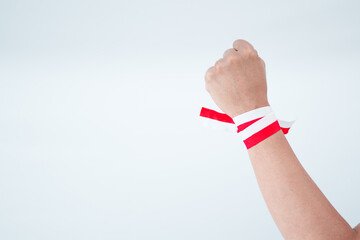 Raised Hand With Red And White Wristband