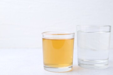 Glasses with clean and dirty water on light table, closeup. Space for text