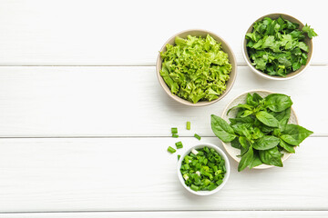 Different aromatic herbs in bowls on white wooden table, flat lay. Space for text