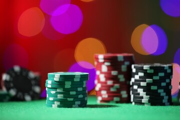 Casino chips on green table against blurred lights, closeup
