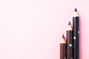 Different eyebrow pencils on pink background, flat lay. Space for text
