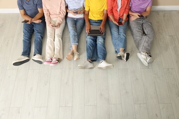 Group of teenagers with laptop and smartphones indoors, above view
