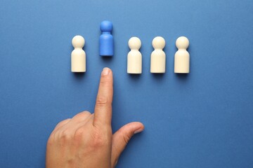 Dismissal. Woman throwing human figure away on blue background, top view
