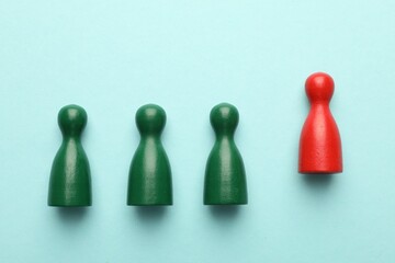 Unemployment. One red figure among green on light blue background, flat lay