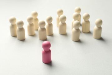 Unemployment. One pink figure among wooden on light background
