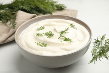 Tasty sour cream with dill on white table, closeup
