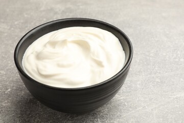 Tasty sour cream in bowl on grey table, closeup