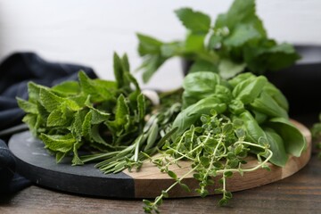 Different fresh green herbs on wooden table, closeup