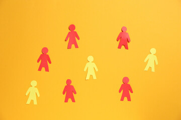 Many human paper figures on orange background, flat lay