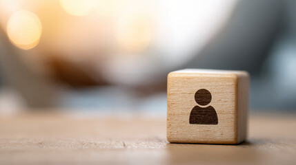 Wooden cube with person symbol on wooden surface with blurred background and warm light creating calm and focused atmosphere