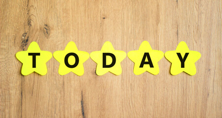 Today symbol. Concept word Today on beautiful yellow paper stars. Beautiful wooden table wooden...