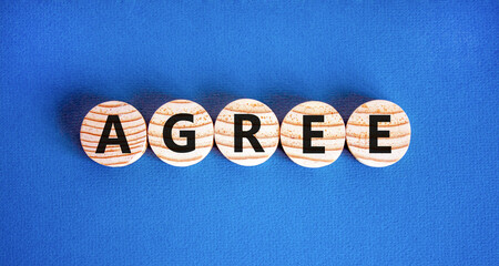 Agree symbol. Concept word Agree on beautiful wooden circles. Beautiful blue table blue background....