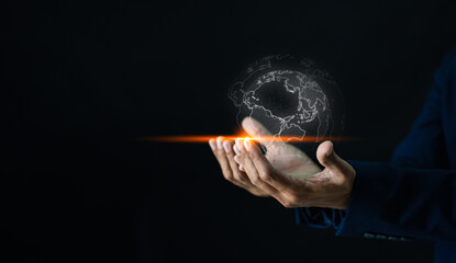 A hand holds a glowing digital globe outline, symbolizing global connectivity and technology in a dark background.