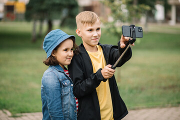 Girl and boy teenagers bloggers influencer records videos from the blog on a smartphone outdoor....