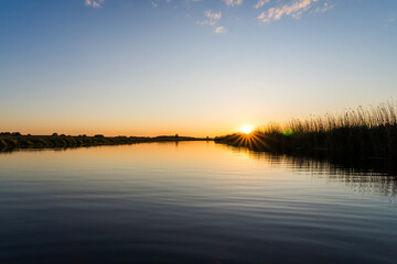 Obraz premium Sunset over the Trebel River with Sun Rays Shining through the Reeds