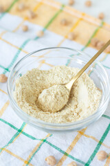 Gluten-free chickpea flour in a bowl with spoon. Close-up.