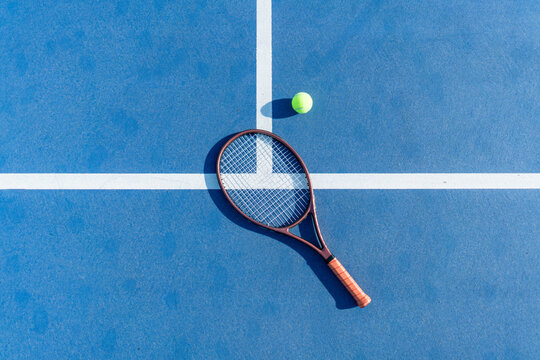High-angle view of tennis racket and ball on court surface