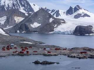 Aerial view of the stark contrast between the red-roofed buildings and the icy waters, with the snow-capped mountains towering in the background, Seymour Island, Antarctica.